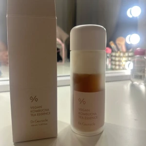 Dr.Ceuracle Vegan Kombucha Tea Essence - Vegan Kombucha Tea Essence från Dr.Ceuracle i en stilren, genomskinlig flaska med vit kork. Innehåller 150 ml essence med en tvåfasig formula i beige och brun. Perfekt för att återfukta och balansera huden med kombuchaextrakt.