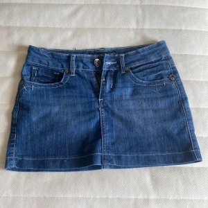 Unik Lågmidjad jeanskjol  - Snygg blå jeanskjol från D*KLIC med klassisk femficksdesign, framfickor och bakfickor med knappdetaljer. Kjolen har synliga vita sömmar och bälteshällor, perfekt för en chill och trendig look. Dragkedja och knapp framtill. Lågmidjad. Kontakta mig om ni har frågor!💞😇