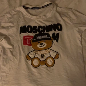Vit Moschino t-shirt med nalletryck - Säljer en vit t-shirt från Love Moschino i bomull med ett stort broderat nalletryck 