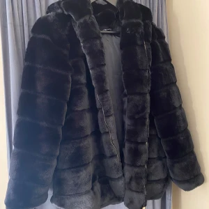 Svart pälsjacka med huva från Voyelles - Säljer en svart pälsjacka från Voyelles med stor huva. 