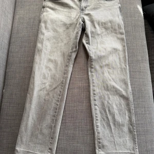 Grå Wrangler Texas jeans straight fit - Säljer ett par gråa Wrangler Texas jeans i straight fit. Klassisk femficksmodell med normal passform och autentisk look. Perfekta för dig som gillar en clean och tidlös stil. 