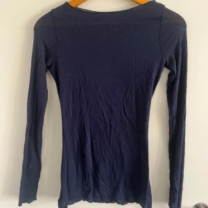 Mörkblå långärmad tröja Intimissimi - Slimmad mörkblå långärmad tröja från Intimissimi. Tillverkad i en ultralätt mix med kashmir som känns supermjuk mot huden. Perfekt att styla med jeans eller kjol för en clean look.