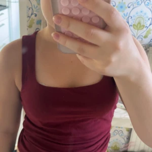 Vinröd linnetopp från Gina Tricot - Vinröd linnetopp från Gina Tricot, basically basics-kollektionen. Toppen har breda axelband, fyrkantig ringning och är figurnära i modellen. 