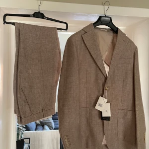 Linnekostym John Henric - Inköpt 2024, helt oanvänd och har hängt i garderoben sedan inköp.  Storlek 46 Färg beige, se bifogad modellbild för korrekt färg
