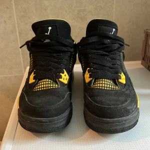 Nike Air Jordan 4 Retro svart/gul - Säljer ett par Nike Air Jordan 4 Retro i svart och gul med coola meshdetaljer och klassisk Jumpman-logga på hälen. Skorna har svarta snören, gula accenter och en robust sula. Perfekta för dig som vill sticka ut med en ikonisk sneaker. Plus det är gamla och hittade på en secondhandbutik. Det kan också passa 36 tror jag 