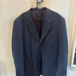 Blå kavaj från Pierre Hector - Snygg blå kavaj från Pierre Hector med klassisk passform och tre knappar framtill. Kavajen har diskreta fickor och är helfodrad med mörkt tyg på insidan. Perfekt för dig som vill ha en stilren look med enkel design.