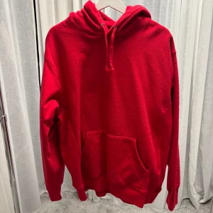 Röd Supreme hoodie med broderad huva - Säljer en röd hoodie från Supreme med broderad logga på huvan. Klassisk känguruficka framtill, snörning i huvan och mjukt material. 