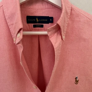 Rosa skjorta från Ralph Lauren - Helt Ny - Säljer en jättefräsch Ralph lauren skjorta i storlek S, modell Slim Fit och färgen rosa då den inte passade! Helt nytt skick - 10/10, inte ens använd och endast testad. Vid minsta lilla fråga tveka inte på att höra av er! Pris kan diskuteras vid snabb affär :)