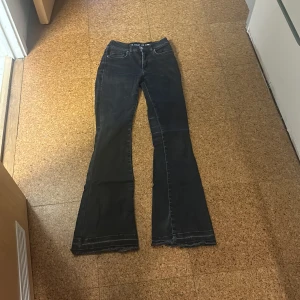 Svarta low flare jeans XS - Snygga svarta jeans med låg midja och flare-ben. Modellen är low flare och längden är 31. Jeansen har råa, fransiga benslut för en cool vibe. Klassisk femficksdesign och tillverkade i stretchig denim som sitter skönt hela dagen.