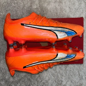 Orangea fotbollsskor från Puma - Puma ultra ultimate supercharge AG/FG dubbar funkar både på naturgräs och konstgräs 9/10 skick använda ba några fåtal gånger.