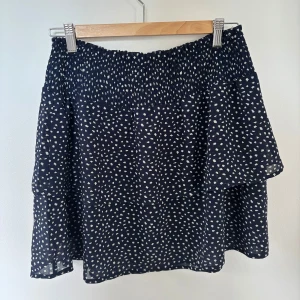 Mörkblå prickig volangkjol från ONLY - Supersöt mörkblå volangkjol från ONLY med vitt prickigt mönster. Kjolen har en smockad midja och volanger nedtill. Använd typ 2 gånger så den är som ny! Storlek S. Säljer då den inte kommer till användning.