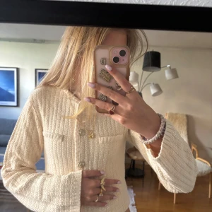 Beige cardigan jacka från H&M XS - Snygg beige cardigan från H&M i storlek XS. Koftan är croppad med lång ärm, har dekorativa guldfärgade knappar framtill och två fejkade fickor. Materialet är stickat och ger en cool, texturerad look. Skriv för fler bilder!