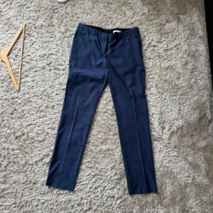 Mörkblå kostymbyxor från BOSS - Snygga mörkblå kostymbyxor från BOSS med klassisk rak passform och pressveck. Byxorna har diskreta bakfickor och är tillverkade i ett tunt, elegant tyg som känns lyxigt. Perfekta för dig som vill ha en stilren och dressad look. Passar på mig och jag är 181cm och 68kg