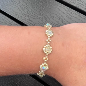 Guldigt armband med glittriga stenar - Superfint armband i guldton med runda, glittriga stenar som är infattade i små pärldetaljer. Stenarna skimrar i olika färger beroende på ljuset och ger ett lyxigt intryck. Perfekt accessoar för att lyfta din outfit med lite extra bling.