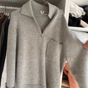 Grå stickad half zip-tröja H&M - Mysig grå stickad tröja från H&M med half zip och krage. Tröjan har en stor bröstficka och ribbade muddar vid ärmslut och nederkant. 