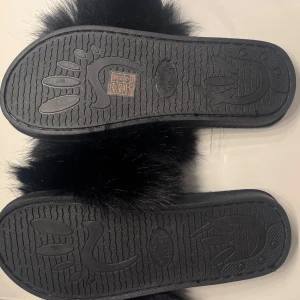 Svarta fluffiga sandaler med päls - Svarta sandaler med breda remmar täckta av mjuk, fluffig pälsimitation. Aldrig använda då dom är i fel storlek 