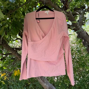 Rosa amningtopp från H&M Mama XL - Supersöt ljusrosa amningtopp från H&M Mama i ribbad bomull. Toppen har lång ärm, v-ringning och omlottdesign som gör den perfekt för dig som vill ha något bekvämt och snyggt. Perfekt för vår och sommar! Storlek XL, men kanske passar en L bättre. Den har ingen prislapp men är aldrig använd, men den är tvättad. 