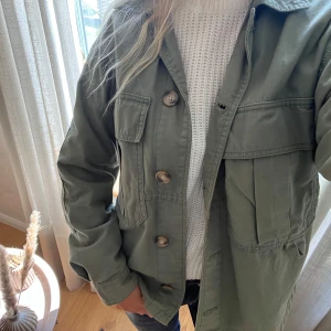 Grön jacka - Säljer en snygg militärgrön jacka med stora bröstfickor och knäppning framtill. Perfekt till hösten!!!