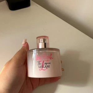 The Lagoon Leilani Eau de Toilette 100ml - Säljer en söt parfym, The Lagoon Leilani från Douglas Cosmetics. Flaskan är rund och genomskinlig med rosa detaljer och blommigt tryck. Innehåller 100 ml Eau de Toilette, tillverkad i Tyskland. Perfekt för dig som gillar fräscha och feminina dofter. Köpt 500 kr i Berlin, säljer den för 350 endast testat!