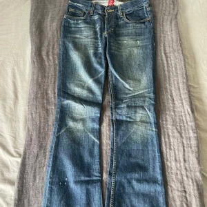 Trendiga bootcut jeans - Säljer ett par snygga jeans i blå tvätt med snygga slitningar och bootcut. Modellen har låg midja och sitter jätte skönt. Skulle säga att de är i storlek S/36 och de passar tyvärr inte mig längre. Perfekta nu inför hösten och vintern! Måttet tvärsöver är 38 cm, innerbenslängd är 77 cm och lårbredden är 25 cm. 