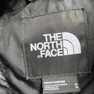 Svart dunjacka The North Face Lhotse - Säljer en svart The North Face 1990 Lhotse dunjacka i storlek M. Jackan är rejält vadderad med klassisk boxig passform, dragkedja framtill och broderad logga på bröstet. Perfekt för kalla dagar och riktigt snygg streetstil.