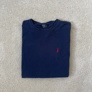 Mörkblå t-shirt från Polo Ralph Lauren - Ralph lauren t-shirt | Skick – 7/10 | Size – XL | Hör av dig vid minsta fråga eller fundering!! Armarna är lite extra korta se bild och ser lite avklippta ut!