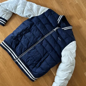 Gant pufferjacka  - Snygg pufferjacka från GANT i mörkblått med vita ärmar, Perfekt nu till vintern🤩❄️ Den är väldigt sparsamt använd och i väldigt bra skick. Storleken är 16 år/176. Priset går att diskuteras vid snabb affär🤝