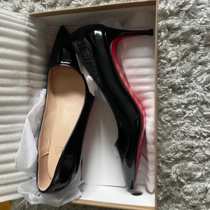 Svarta Louboutin pumps med röd sula - Snygga svarta pumps från Christian Louboutin i lackat skinn med ikonisk röd sula. klack:7cm, storlek:39 Säljer dessa eftersom dem inte passar mig och fick dem i födelsedags present. Helt nya🩷