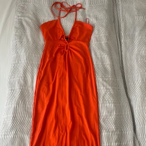 Orange långklänning från Gina Tricot - Snygg orange långklänning från Gina Tricot med smala axelband som knyts i nacken och v-ringning. Använt 1 gång, sitter jättebra 