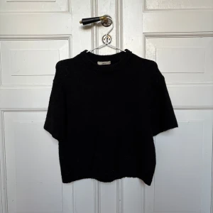 Svart stickad tröja Gina Tricot XS - Svart stickad tröja från Gina Tricot i storlek XS. Modellen har korta ärmar och rund halsringning med ribbad kant. Mjuk och lite fluffig känsla, perfekt för lager-på-lager. Enkel och stilren design som funkar till många olika looks. 💕💕