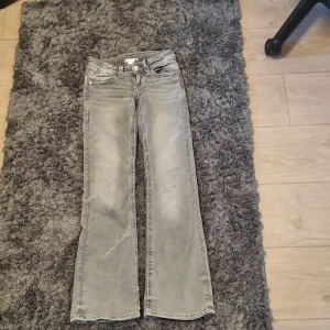 Grå bootcut jeans Gina Tricot 146 - Snygga grå jeans från Gina Tricot i storlek 146. Modellen har bootcut-ben och klassisk femficksdesign med coola detaljer på bakfickorna. Jeansen är i mjukt denimtyg och passar perfekt till en avslappnad stil.