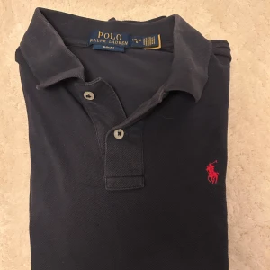 Fet Ralph lauren piké 🔥🔥🙌🙌🙌 - Klassisk mörkblå pikétröja från Polo Ralph Lauren i slim fit-modell. Tröjan har korta ärmar, krage och två knappar framtill samt den ikoniska röda loggan broderad på bröstet. Tillverkad i bomull för en skön och luftig känsla. Pris kan diskuteras 🙌🙌🙌🙌🙌