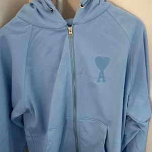 Ljusblå hoodie från Ami Paris - Säljer en ljusblå hoodie från Ami Paris med dragkedja och huva.Storlek L