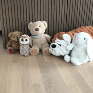 Brun nallebjörn med rutiga detaljer - Söt brun nallebjörn med mjuk päls och rutiga tygdetaljer på tassarna. Nallen har en röd rosett runt halsen och är perfekt som gosedjur eller dekoration.