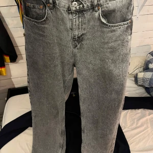 Grå Jeansbyxor - Snygga grå jeansbyxor från Grunt med en klassisk design. De har en rak passform och är perfekta för en avslappnad stil. Byxorna har en knappgylf och är tillverkade i ett slitstarkt denimtyg. Storlek 27 som är XS-S