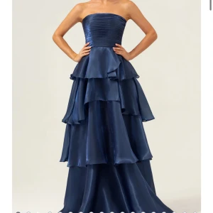 Marinblå axelbandslös långklänning med volanger - Säljer världens finaste marinblåa klänning med flera lager volanger. Klänningen har en glansig finish och markerad midja, perfekt för bal! Endast testad💙💙 använd inte köp nu!