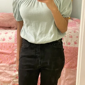 Ljusgrön offshoulder topp från KappAhl - Säljer en ljusgrön offshoulder topp från KappAhl med puffiga korta ärmar och smockad resår vid hals och ärmslut. Toppen har en luftig och lätt struktur, perfekt för varmare dagar.
