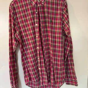Rutig skjorta från Polo Ralph Lauren - Säljer en färgglad rutig skjorta från Polo Ralph Lauren i slim fit. Skjortan har långa ärmar, klassisk krage och knäppning framtill. Perfekt för dig som gillar stilrena och färgstarka plagg.