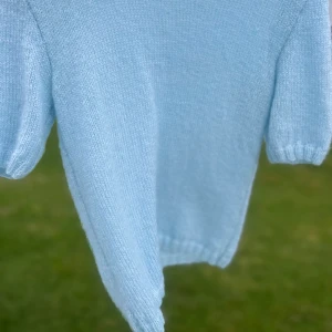 Ljusblå stickad kortärmad tröja - Supermjuk ljusblå stickad tröja med korta ärmar och rund halsringning. Perfekt för sommarens svalare dagar. Enkel och stilren design som passar till det mesta. Den är hemmastickad och oanvänd 