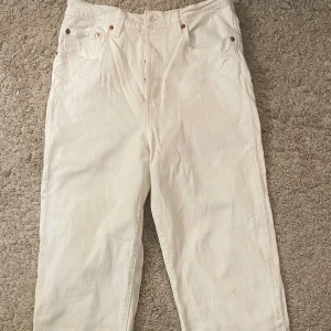 Vita jeansbyxor från Levi's - Säljer ett par vita jeansbyxor från Levi's med klassisk femficksdesign och raka ben. Byxorna har normal passform och är tillverkade i kraftig denim. Perfekta för dig som gillar stilrena och tidlösa plagg. Fråga gärna för flera bilder!!!!