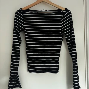 Svartvit randig långärmad tröja med slitsar i ärmen - Säljer en svart långärmad tröja med vita horisontella ränder. Tröjan har en tight passform och är tillverkad i ett stretchigt material. Perfekt för dig som gillar klassiska mönster och enkel stil. 