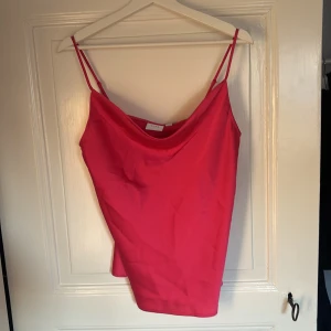 Rosa slikes topp! - Säljer en snygg rosa silkestopp från Vila med tunna axelband och draperad urringning. Linnet har en enkel, elegant design och är tillverkad i ett mjukt, slätt material som ger ett fint fall. 