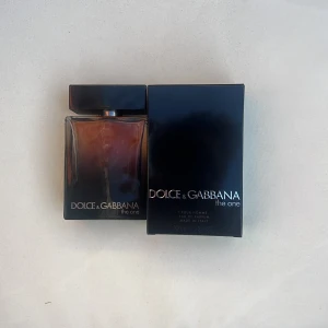 Dolce & Gabbana The One Eau de Parfum - Säljer en elegant herrparfym, Dolce & Gabbana The One, i en stilren brun glasflaska med svart lock. Flaskan rymmer 100 ml och har en sofistikerad doftprofil. Perfekt för den som vill ha en tidlös och maskulin doft.