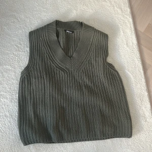 Grön stickad väst från Gina Tricot - Snygg grön stickad väst från Gina Tricot med v-ringad design. Perfekt för lager-på-lager och ger en stilren look. Passar bra till både skjorta och t-shirt.