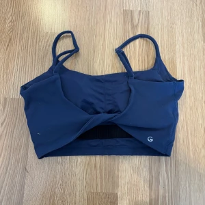 Mörkblå sportig linnetopp med twist baktill - Säljer en mörkblå linnetopp med smala axelband och twistad detalj. Toppen har en sportig look och är perfekt för träning.🩷