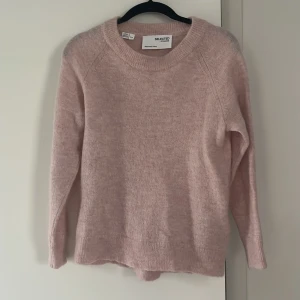 Ljusrosa stickad tröja från Selected Femme - Mysig ljusrosa stickad tröja från Selected Femme. Tröjan har rund halsringning och långa ärmar, perfekt för kyliga dagar. Enkel och stilren design som passar till många olika outfits.