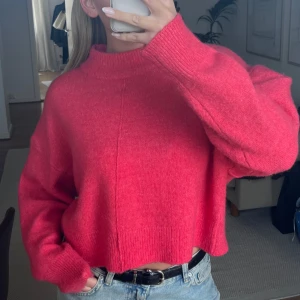 Rosa stickad tröja - Säljer en snygg rosa stickad tröja med croppad passform. Tröjan har långa ärmar och en hög halsringning. Oanvänd från Gina