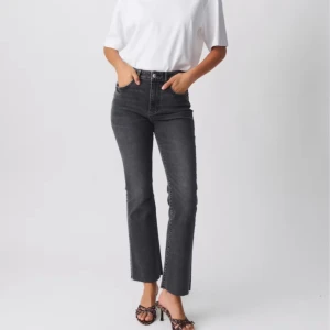 Svarta/grå kick flare jeans - Snygga svarta jeans med rak passform och hög midja. Perfekta för en stilren look. Dom är helt nya i storlek 36 från Gina tricot.