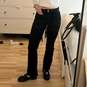 Svarta jeans från Maje - Snygga svarta jeansbyxor från Maje med flätade detaljer vid fickorna och midjan. Byxorna har en hög midja och en rak passform som ger en stilren look. Perfekta för att lyfta vilken outfit som helst.