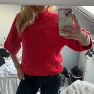 Röd stickad tröja - Säljer en röd stickad tröja med trekvartsärm. Perfekt för kyligare dagar och ger en mysig känsla. Passar bra till jeans eller kjol.
